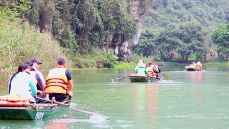 people rowing boats through scenic river landscape