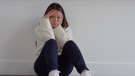 Stressed-Or-Anxious-Woman-Suffering-With-Depression-And-Anxiety-Leaning-Against-Wall-Sitting-On-Floor-At-Home-1