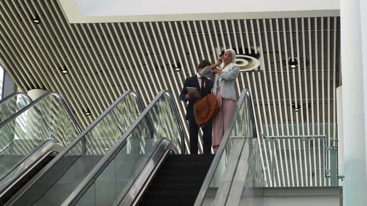 Unge forretningsfolk på en rulletrappe i en moderne bygning