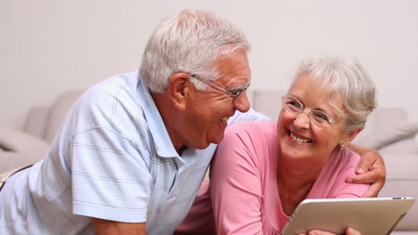 senior couple lying on floor using tablet pc