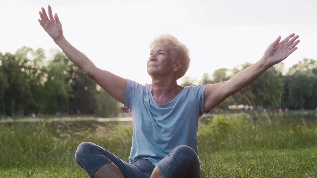 Senior woman meditating in the park by the lake