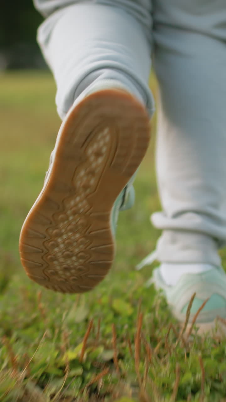 closeup sneakers walking on green grass, slow steady stride across park meadow, casual sweatpants and mint trainers, focus on sole pattern and foot motion, peaceful morning mood and mindful pace