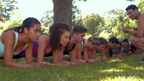 in high quality format fitness group planking in park with coach