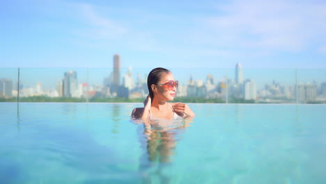 Frau-Glatte-Nasse-Haare-Im-Pool-Auf-Dem-Dach-Mit-Blick-Auf-Die-Skyline-Von-Bangkok,-Kopierraum-In-Zeitlupe