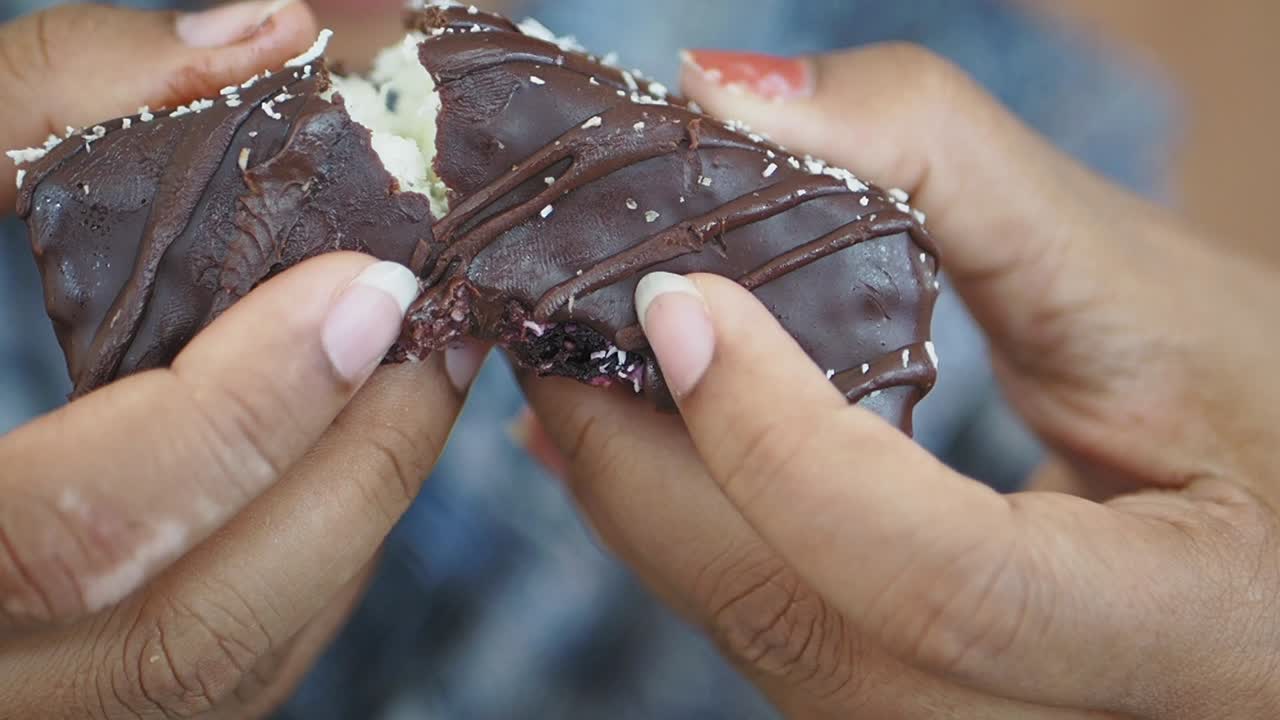 Chocolate Coconut Bar Being Eaten by Hands