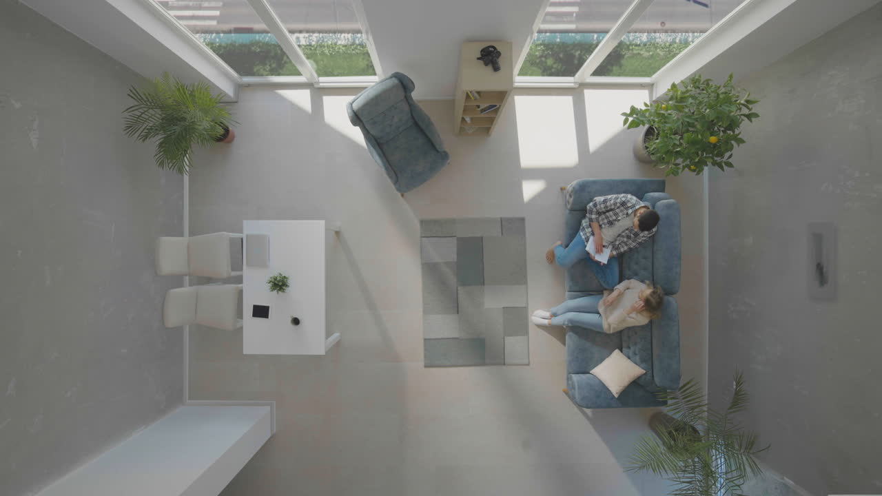 hombre sentado en el sofá y mujer viniendo