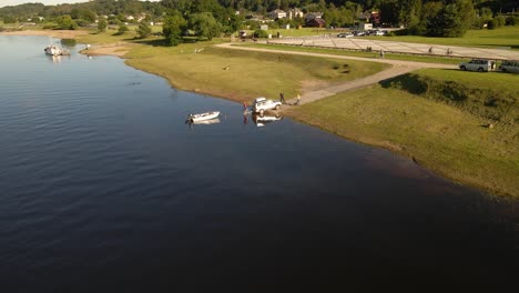 White-car-with-a-tow-getting-a-boat-in-river-Nemunas-near-Kaunas,-Lithuania