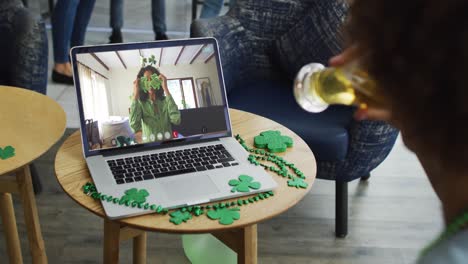 Man-having-beer-on-laptop-video-call-celebrating-st-patrick's-day-with-friends