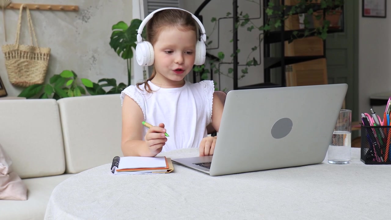 Little Girl Learning Online with Laptop and Headphones at Home
