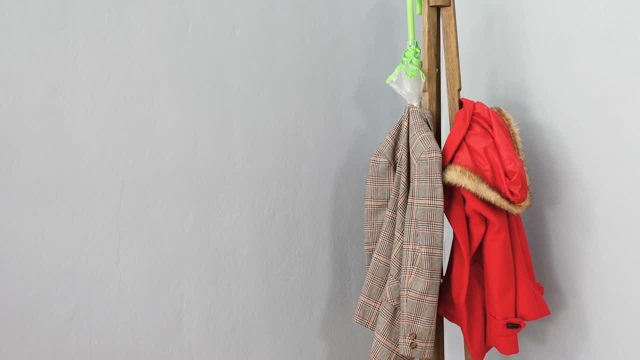 ropa de abrigo, paraguas y botas wellington en el soporte de madera 4k