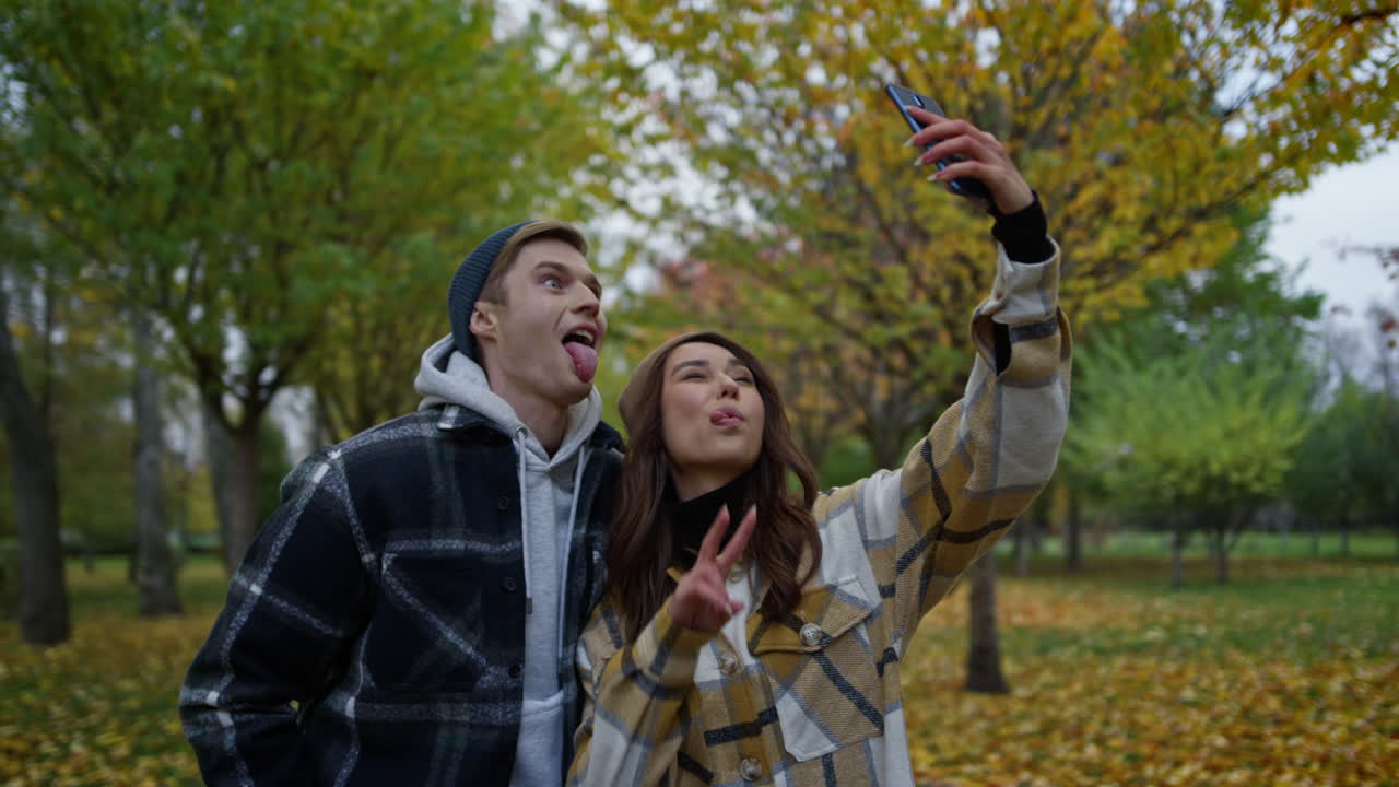 amantes felices y divertidos tomando selfies al aire libre