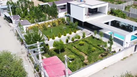 vuelo alrededor de la casa de color blanco paredes altas vegetación eco diseño de paisaje y arquitectura moderna minimalista casa de lujo día tiempo aéreo maravillosa amplia vista de concepto de bienes raíces piscina en el techo