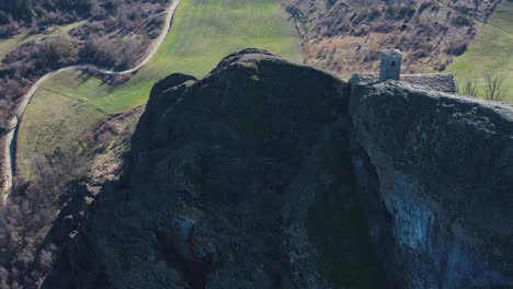 Aerial-footage-of-Pietra-Perduca,-volcanic-rock,-church-set-at-top-stone-immersed-in-countryside-landscape,-cultivated-land-in-Val-Trebbia-Bobbio,-Emilia-Romagna,-Italy