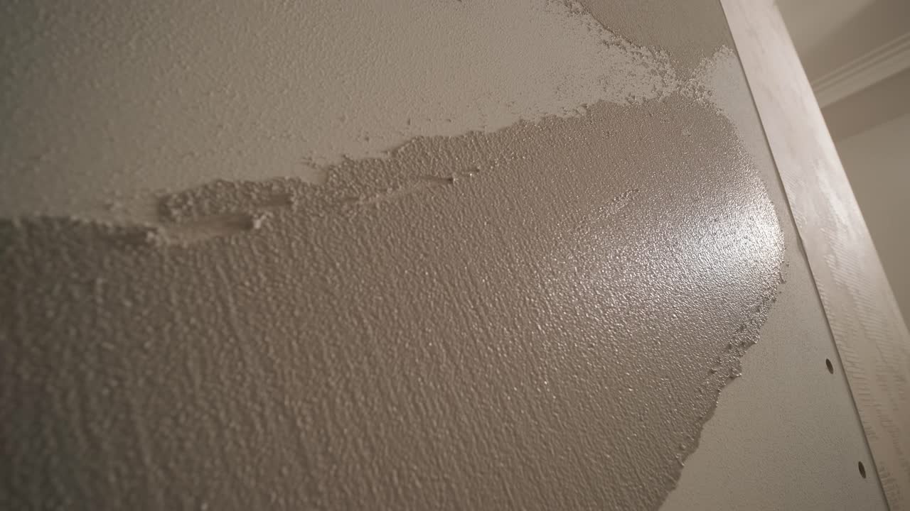 Man plastering the walls with finishing putty in room with putty spatula