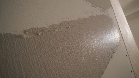 man plastering the walls with finishing putty in room with putty spatula