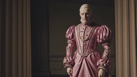 recreación histórica que muestra a un noble con un elegante vestido rosa con decoraciones de perlas, de pie en un interior vintage con columnas y cortinas