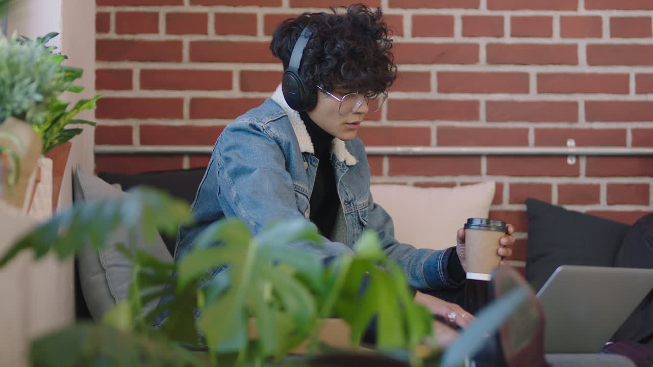 joven estudiante de negocios hispano usando computadora portátil estudiando en línea disfrutando de trabajar escuchando música relajándose en un moderno lugar de trabajo de oficina usando auriculares