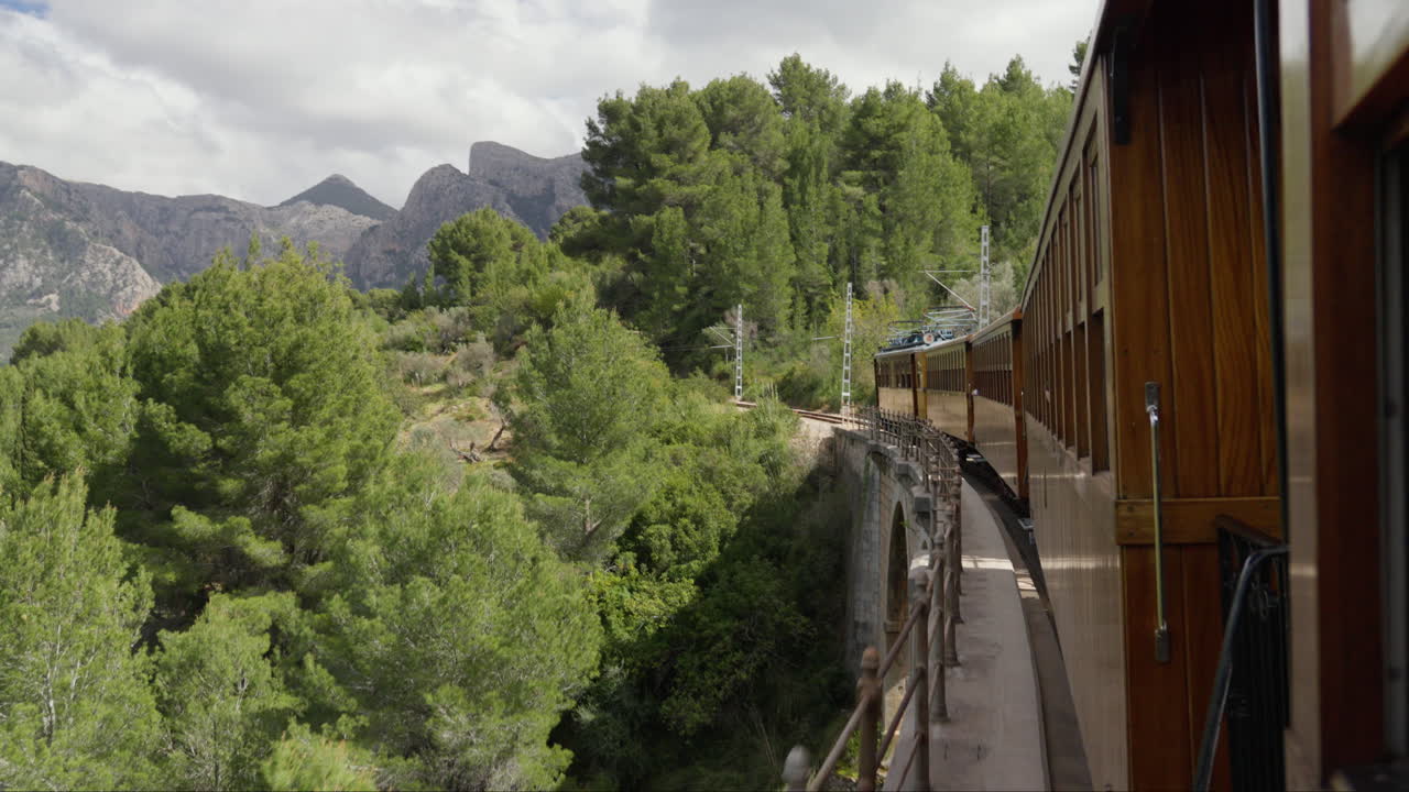 tren vintage cruzando un puente en soller, mallorca con un telón de fondo panorámico
