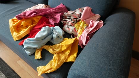 pile of children's clothes on a sofa