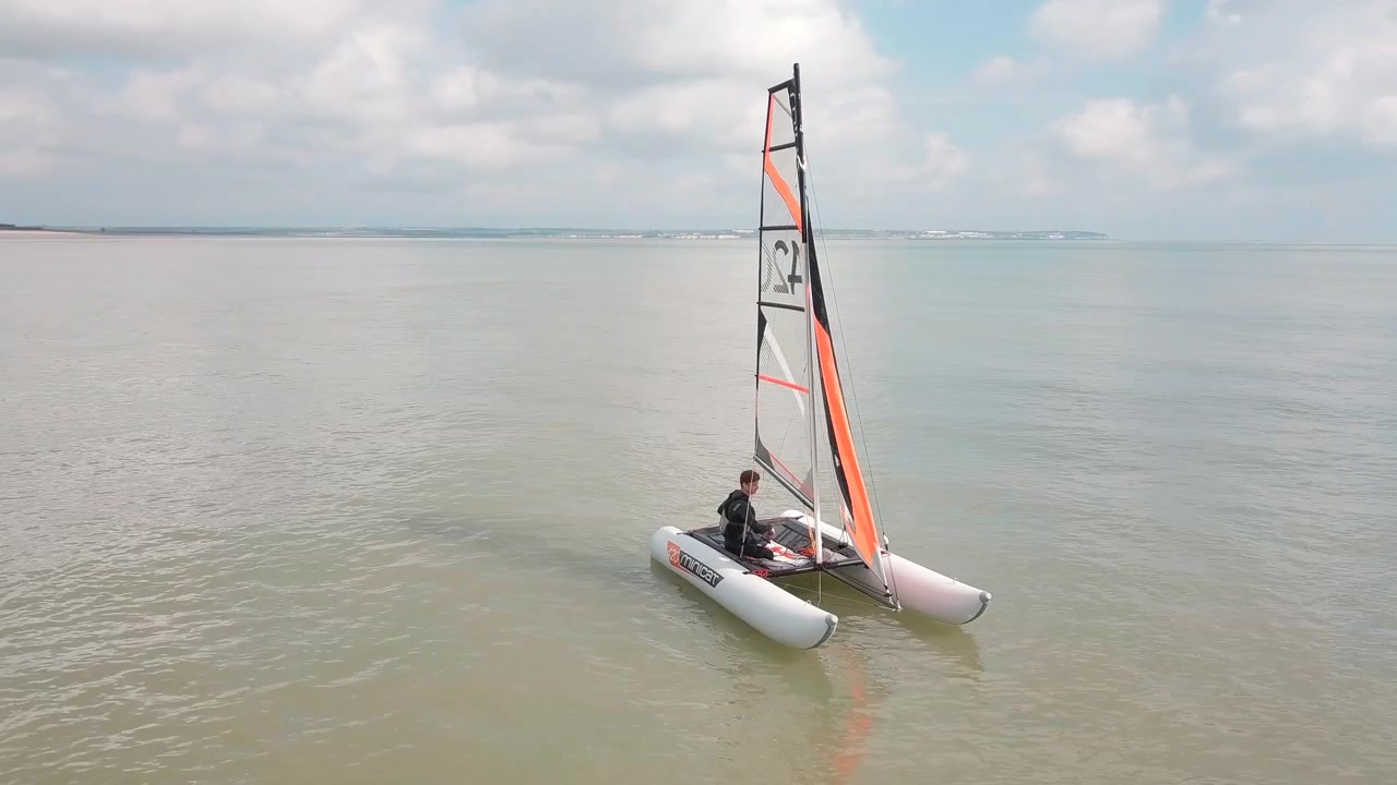 Homme naviguant sur son catamaran en mer, bateau immobile. Drone survolant le bateau, magnifique paysage côtier.