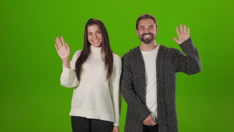 positive couple waving with hands over green background