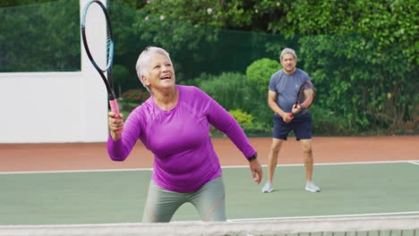 Video-De-Una-Feliz-Pareja-Birracial-De-Ancianos-Durante-El-Entrenamiento-En-Una-Cancha-De-Tenis.