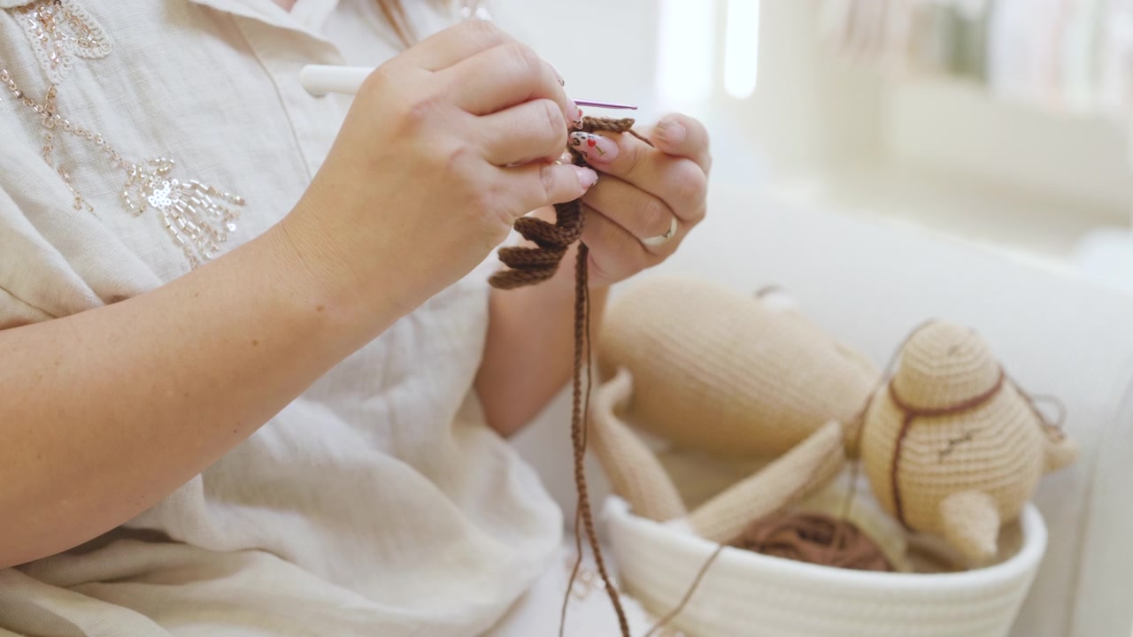 A shot showing a person's hands working with crochet and dark yarn, creating a piece by hand
