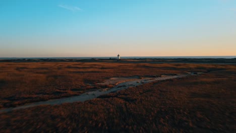 aerial forward shot of natural landscape with lighthouse and ocean in background at sunset time - provincetown, massachusetts