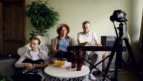 young musical group bloggers are recording their practice on camera, vocalist is singing, musicians are playing the guitar and the keyboard. music and blogging concept.