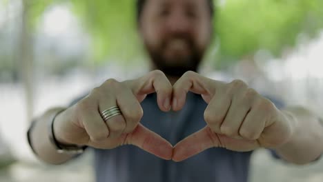 hombre mostrando el gesto del corazón de la mano al aire libre