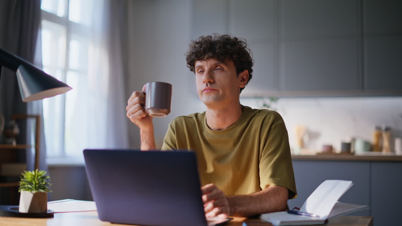 Overworked man sipping beverage at workplace closeup. Pensive author drinking