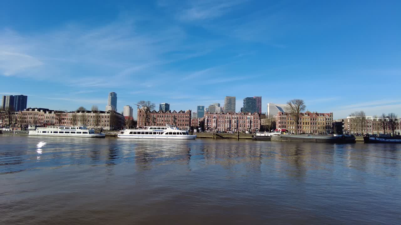 Aerial view of Rotterdam, Netherlands, showing the iconic Erasmus Bridge, boats on the river, and the skyline of this modern city under a clear blue sky—capturing the vibrant waterfront scene