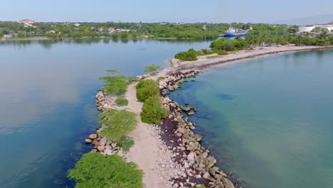 Aerial-flyover-Neiba-Bay-in-with-jetty-and-clear-water-of-sea-during-sunny-day---Barahona,-Dominican-Republic