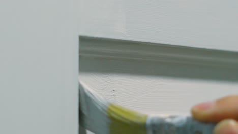 close up of hand with small paintbrush applying white paint decorating home 4k