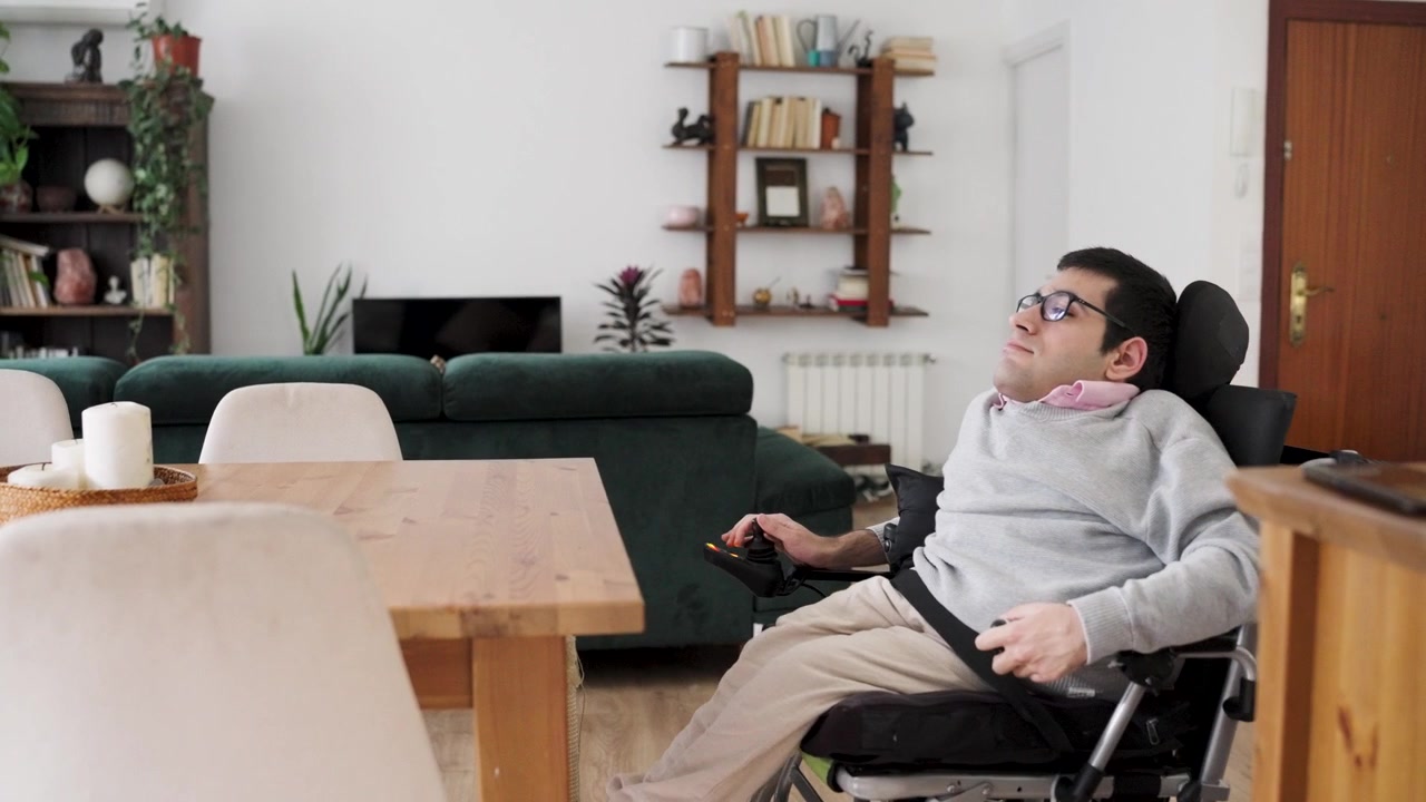 Giovane con disabilità che si rilassa su una sedia a rotelle elettrica a casa.