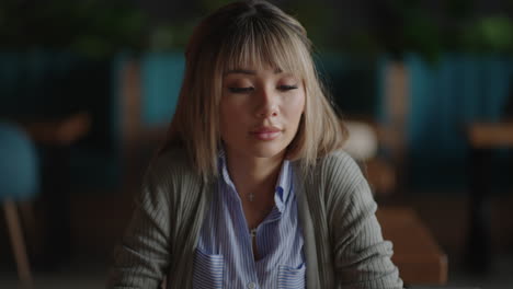 portrait of a beautiful young and attractive asian woman is sitting and looks worried and serious as she broods in front of her laptop computer during the day.