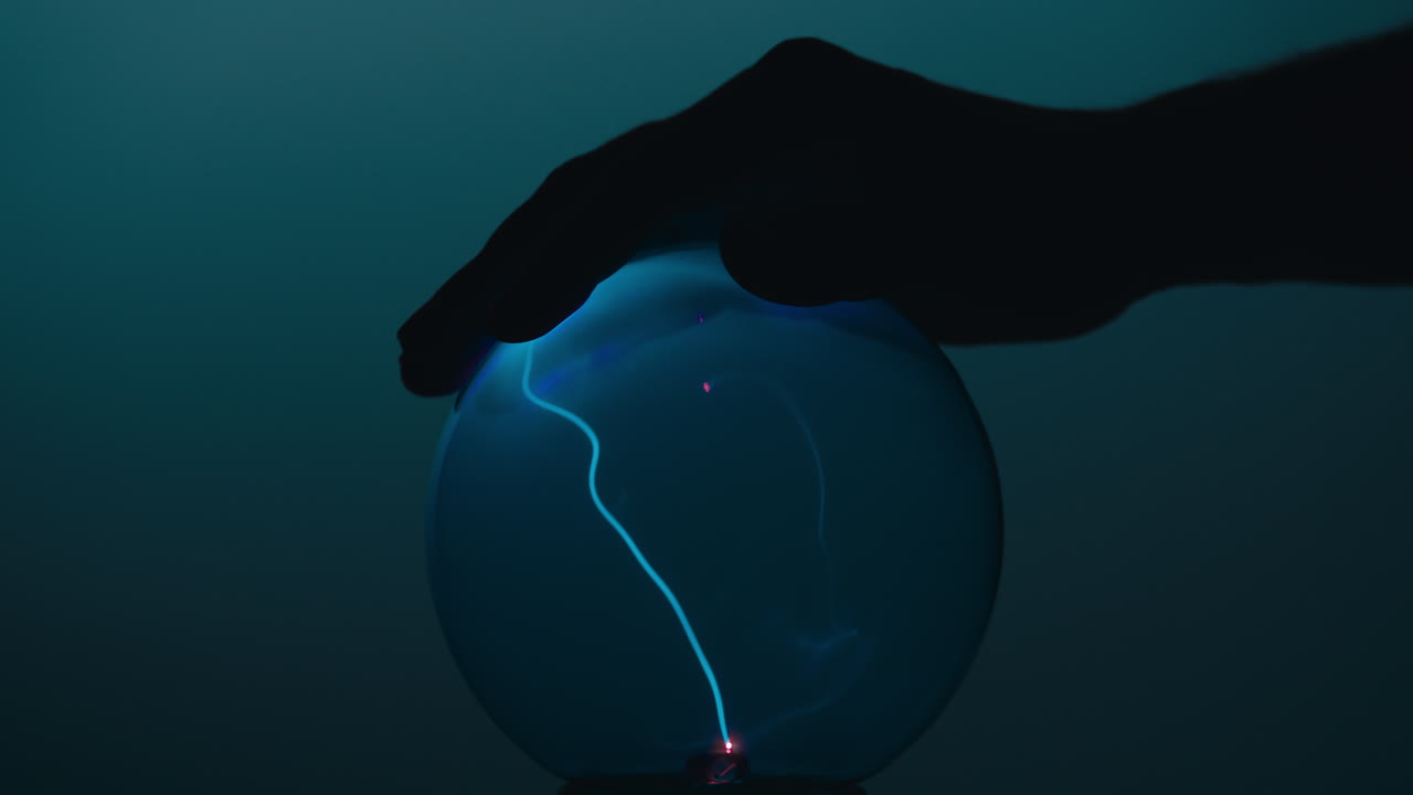 손이 플라즈마 공 위에 떠다니고 있습니다.