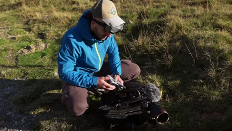 drone operator checking controller for fpv drone as he's knelt on grass in valmalenco