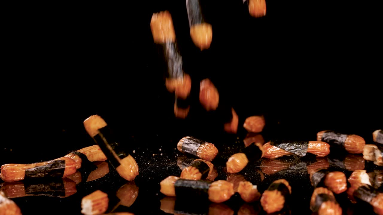 Crunchy Japanese rice crackers drop onto a glossy black surface, captured with dramatic studio lighting