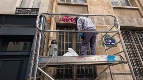 a worker cleans windows on a scaffold in the city.