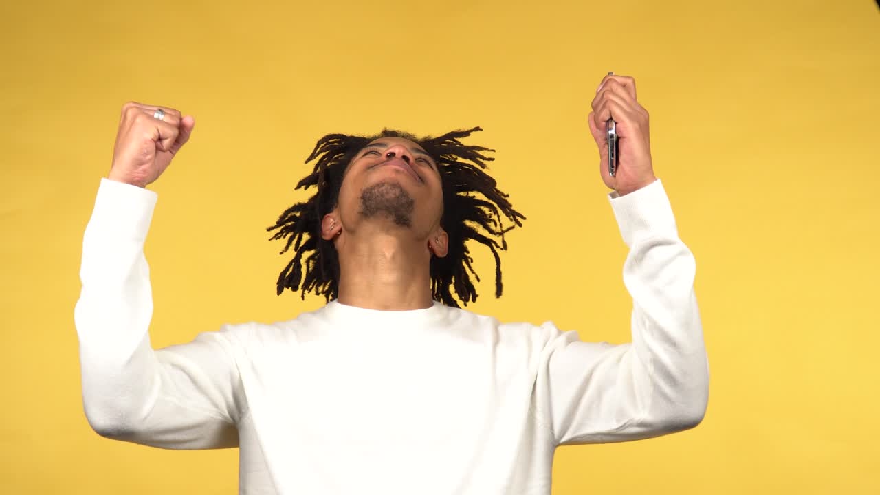 Young black male reacts successfully to something he sees on his phone