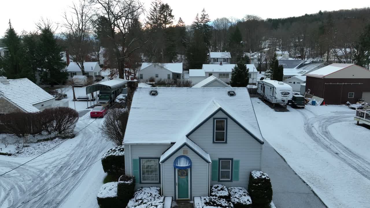 Aerial rising shot of small, quaint house covered in snow