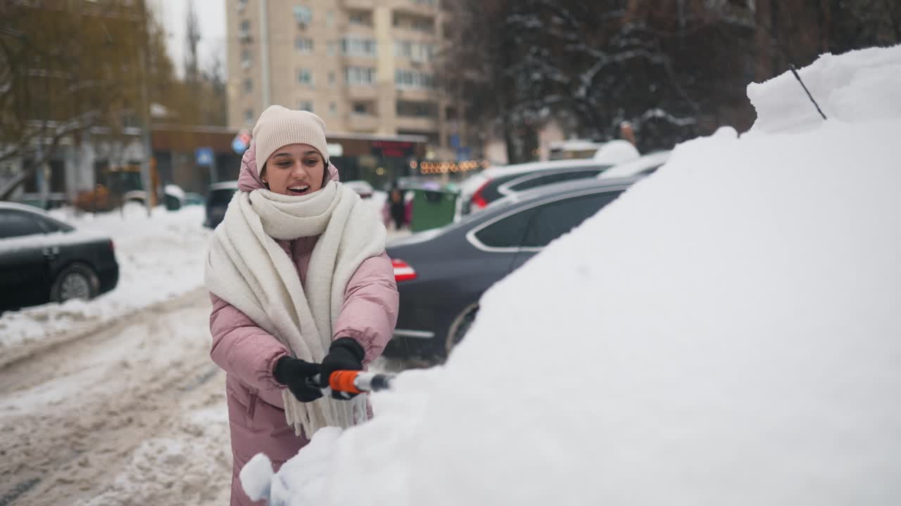 mujer limpiando la nieve de un coche en una calle nevada de la ciudad