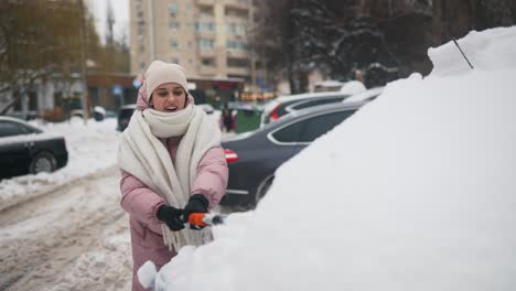 woman shoveling snow from a car in a snowy city street