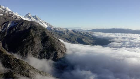 Jade-Dragon-Mountain-Shanzidou-peak-rising-above-clouds,-Yunnan-China,-4K-aerial