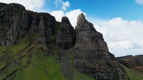 aerial pull away and tilt down across jagged rocks of the scottish highland hidden in the shade