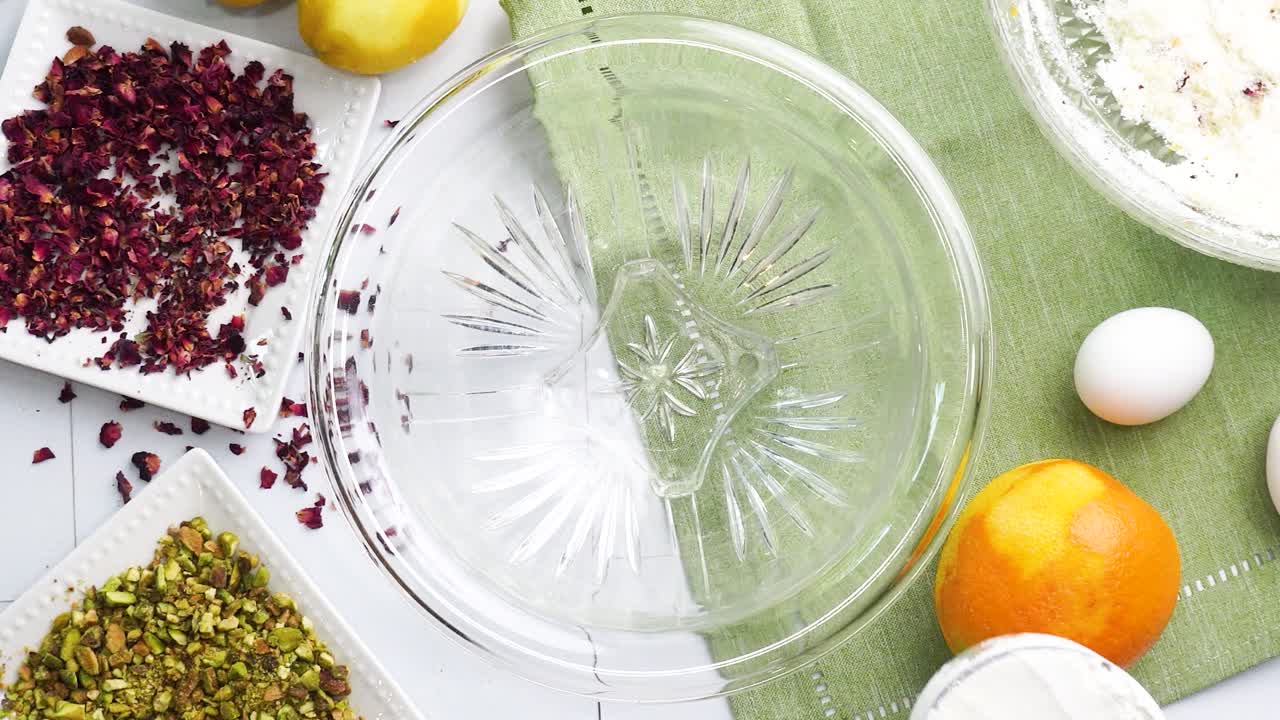 Baking a dessert called Persian Love Cake made with rose petals and pistachios. Cake with white glaze frosting. Mixing in the flour to the batter. Beautiful cake for tea time or celebration