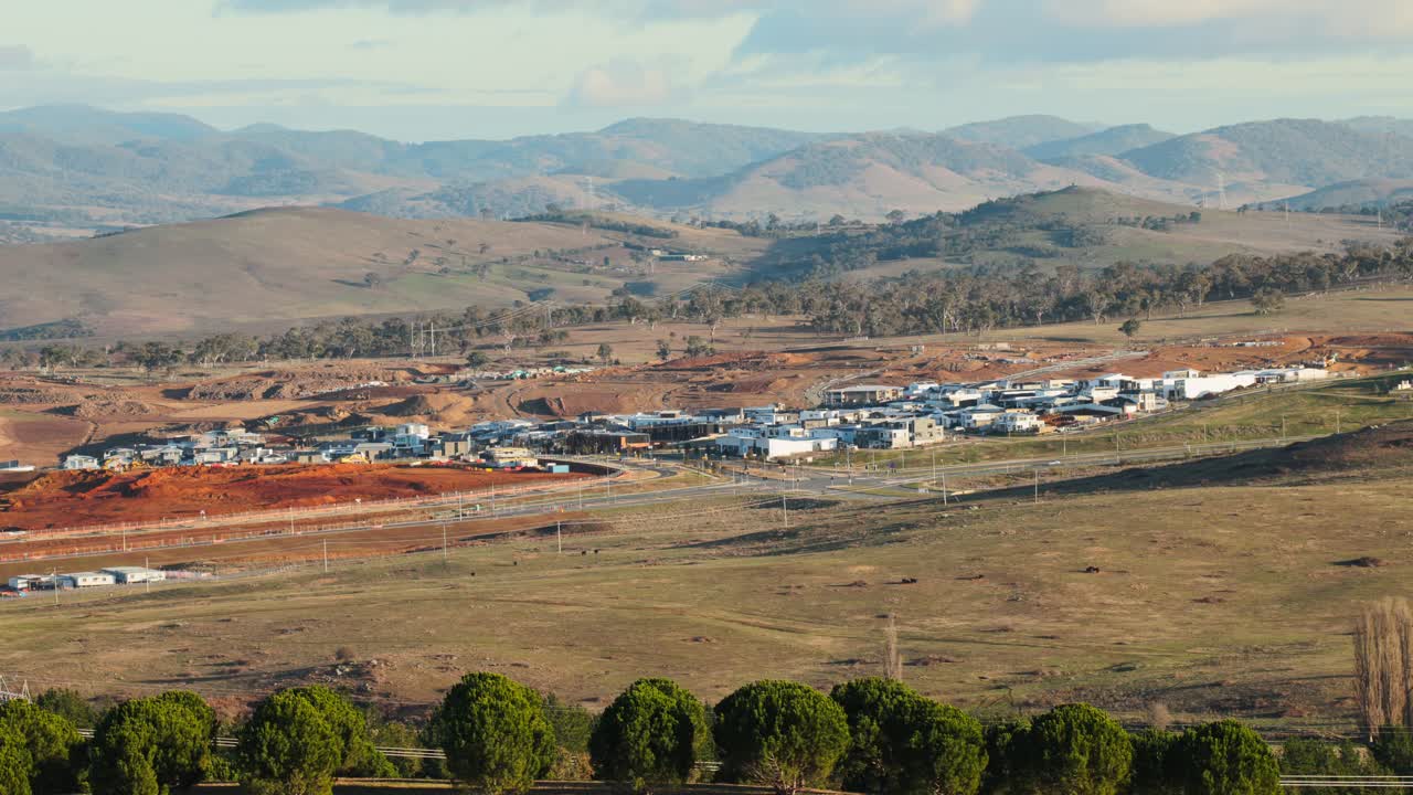 Aerial view of an expanding Canberra suburb with completed homes, marked construction zones, and future lots