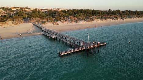 People-enthusiastically-jumping-from-jetty-at-Coogee-Beach-in-Perth-City,-Western-Australia