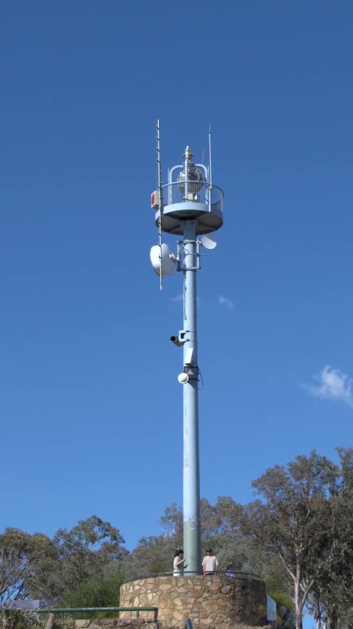 Una panoramica rivela un'alta torre di comunicazione metallica contro un cielo azzurro limpido